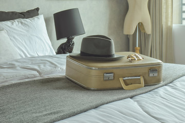 Retro style travel bag, hat and sunglasses on bed in hotel guestroom