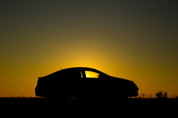 Naklejka na ściany i meble Silhouette of sedan car on the background of beautiful sunset