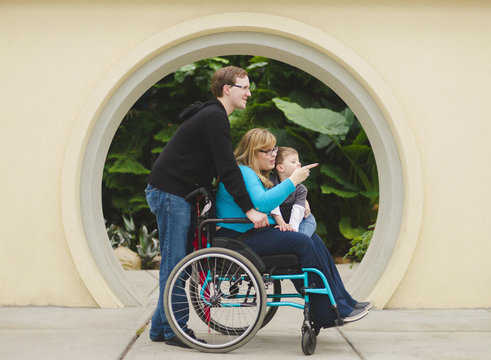 Man pushing paraplegic wife and son