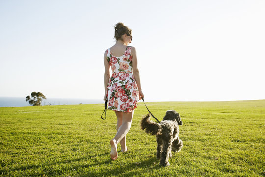 Caucasian woman walking dog in field