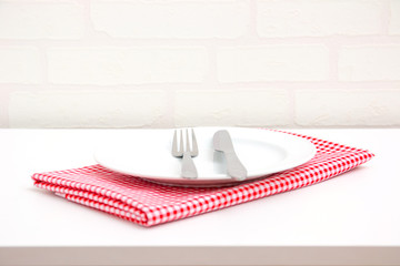 Empty plate on red tablecloth over table with brick wallpaper background - Powered by Adobe