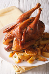 Whole baked chicken with lemon and thyme close-up on a plate. vertical
