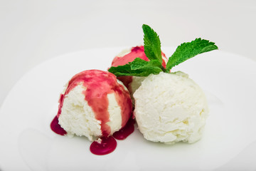 Three scoops of ice cream with strawberry syrup and mint on a white plate, white background, close-up