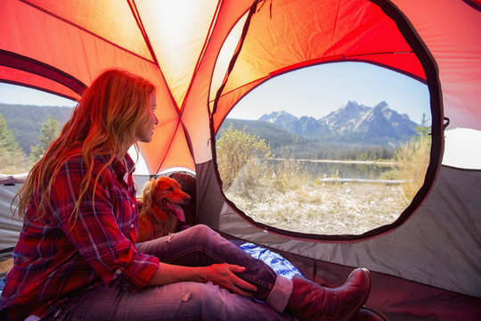 Caucasian woman and dog in camping tent