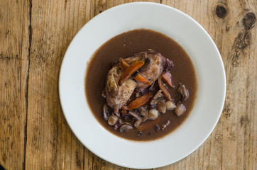 Coq au vin natural light from on plate from above. Classic French chicken dish prepared served with vegetables in red wine 