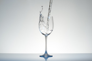 Water pouring into a wineglass creating swirl with splashes.