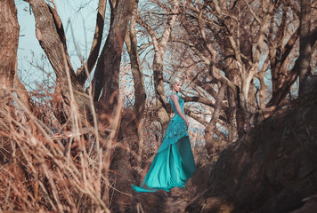 beautiful fairy in a long turquoise dress walks among the enchanted forest , princess, queen,...