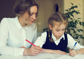 Mother helping daughter with homework at home. Vintage effect.