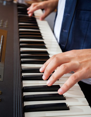 Obraz na płótnie Canvas Man's Hands Playing Piano In Recording Studio
