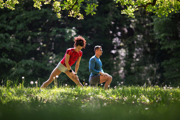 Fototapeta premium In the midst of nature's tranquility, a young couple takes a moment to stretch after jogging, embracing the serene ambiance that surrounds them.