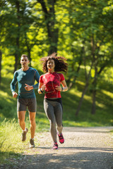 Amidst nature's beauty, a young couple enjoys a refreshing jogging, savoring the fresh air and beautiful spring surroundings.