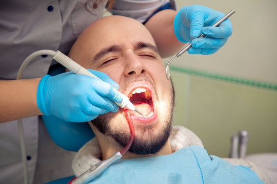 close up photo of handsome guy treats caries teeth in the dental