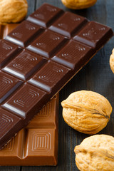Milk, black chocolates with walnuts  on dark wooden boards