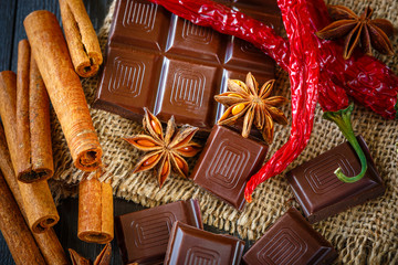 Dark and milk chocolates with dry oranges, chili pepper, cinnamon and anise on burlap on rustic...