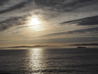 Paisaje escénico sobre un atardecer en el mar, con nubes y luz dorada reflejándose en el mar azul, viajando por Santander en España, primavera de 2016.
