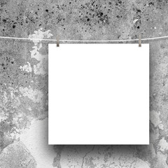Close-up of one blank square frame hanged by pegs against grey weathered concrete wall background