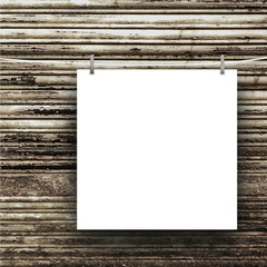 Close-up of one blank square frame hanged by pegs against brown rusty metal shutter background