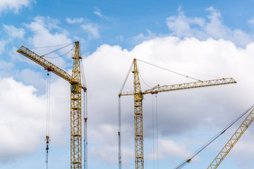 Two construction cranes on  blue sky background