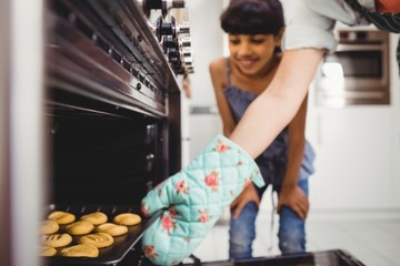 Cropped hand of woman placing cookies in oven