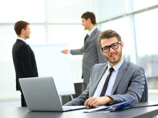 Portrait of a handsome young business man with people in background at office meeting