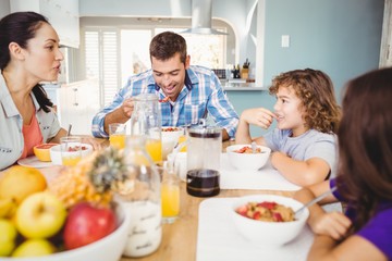 Happy family eating breakfast at table