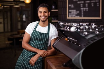 Smiling barista leaning against counter