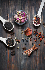 assortment of dry tea in spoons, on wooden background