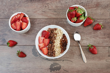 Healthy breakfast -yoghurt with oat flakes, raisins, strawberries, muesli. Fruit breakfast, wooden background