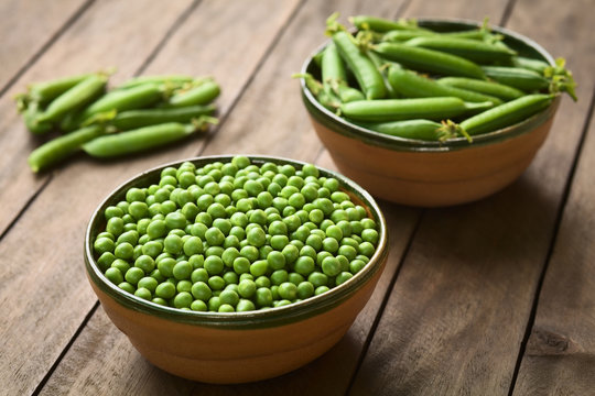 Peas (lat. Pisum sativum) and closed peapods in bowls (Selective Focus, Focus into the middle of the peas)