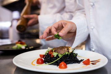 Chef garnishing meal on counter
