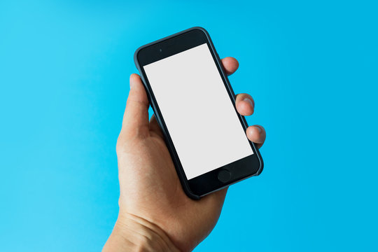 Hand holding black smartphone with blank screen on blue background