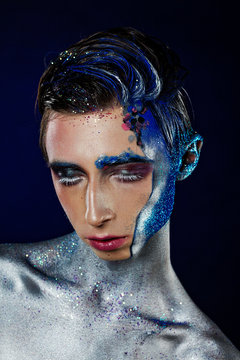 Crazy young androgyne man with face art and closed eyes. SPACEMAN. Freak person. Sperm on face. Tinsel creative blue makeup. Intersex and anorexia concept. Space for logo
