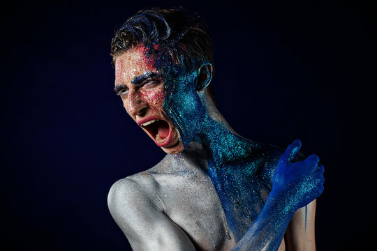Crazy Screaming androgyne man with face art. Aggressive. Freak person. Tinsel creative blue makeup. Intersex and anorexia concept. Space for logo. HOMOSEXUALITY