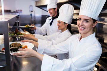 chefs handing dinner plates through order station