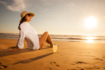 Fototapeta na wymiar Young woman lying in straw hat in sunglasses on beach