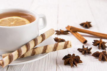 cup of tea with lemon, biscuits and spices