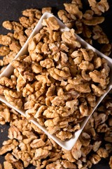 Top view on white bowl full of walnuts on slate stone