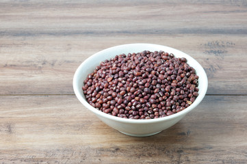 Fototapeta na wymiar Red adzuki beans on a white bowl with wooden table.