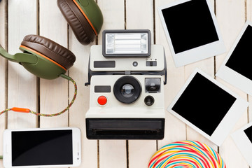 Top view of a retro camera and frames, isolated on white wooden desk.