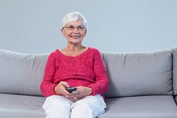 Senior woman sitting and watching television at home