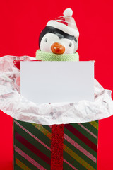 close-up image of snowman with blank placard and christmas gift box.