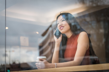 Young woman sitting at caf&egrave; and talk to the phone