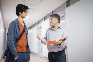 Professor with notebook talking to a student