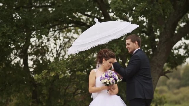 The groom spinning around bride with white umbrella