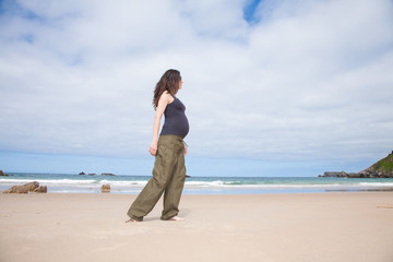 grey shirt pregnant walking next to ocean