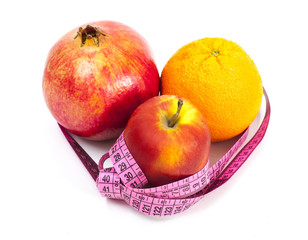 Diet concept:  orange pomegranate apple and measuring tape on white background
