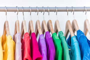 Fashion clothes on clothing rack - bright colorful closet. Closeup of rainbow color choice of...