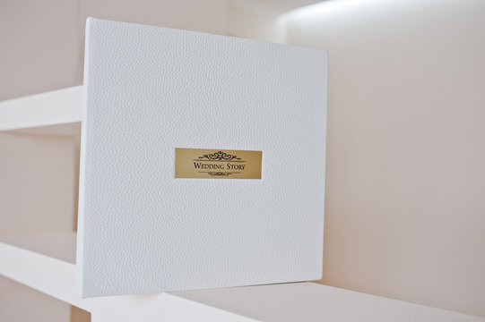 White leather wedding album with golden metallic insert text Wed