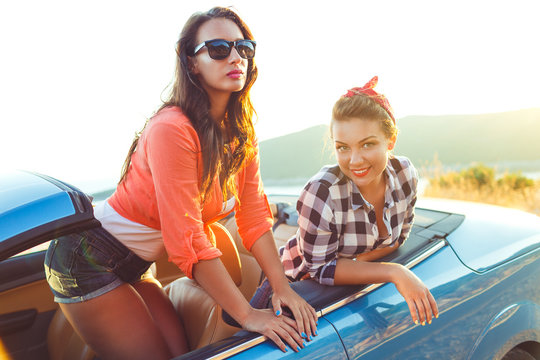 Two young happy girls having fun in the cabriolet outdoors