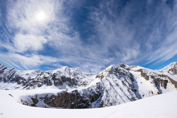 Sun star glowing over snowcapped mountain range, italian Alps